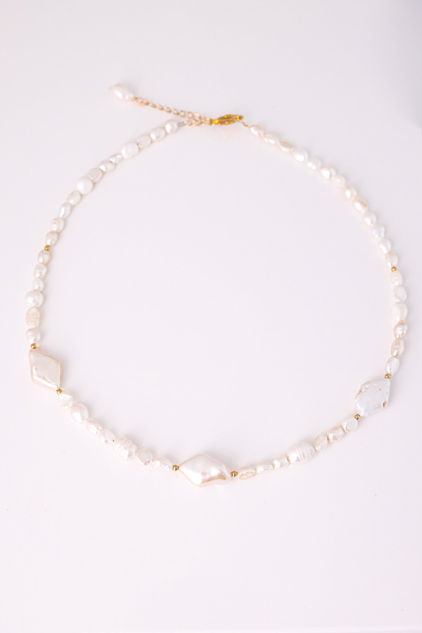 שרשרת SHAI פניני בארוק, מונחת שטוח על לבן. משולבות 3 פנינים שטוחות, חרוזי זהב וסוגר מוזהב.