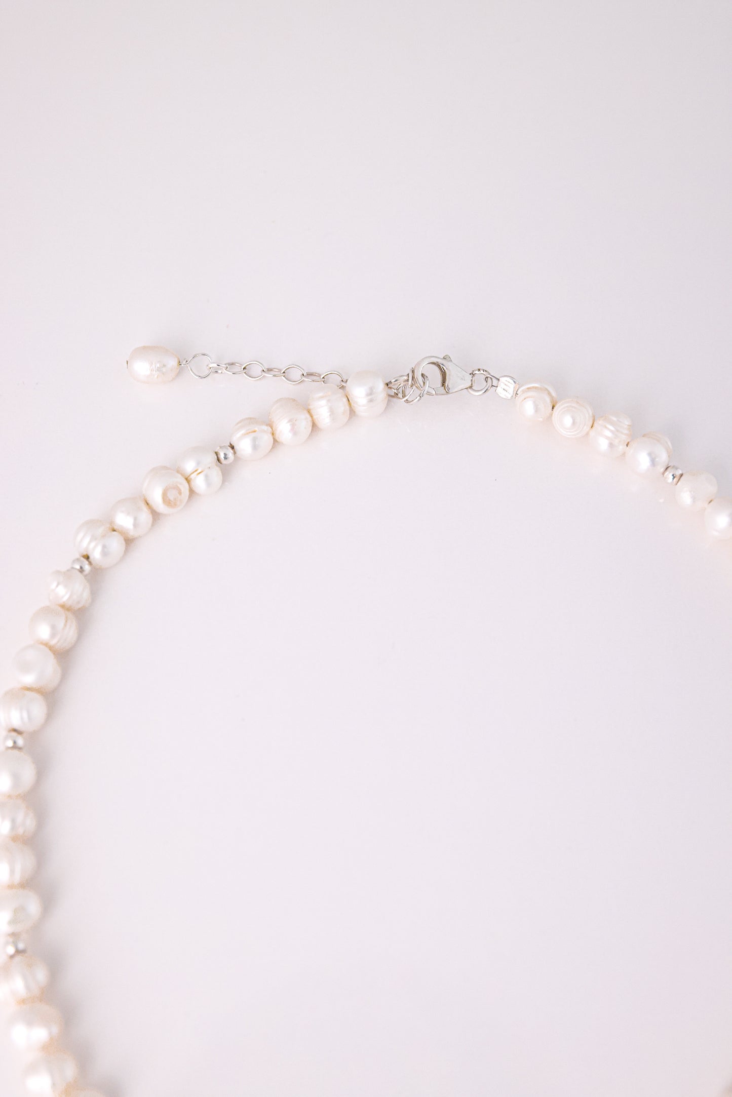 תקריב של סוגר הכסף ושרשרת הארכה של שרשרת GEFEN NECKLACE עם פנינת מים מתוקים בסוף.