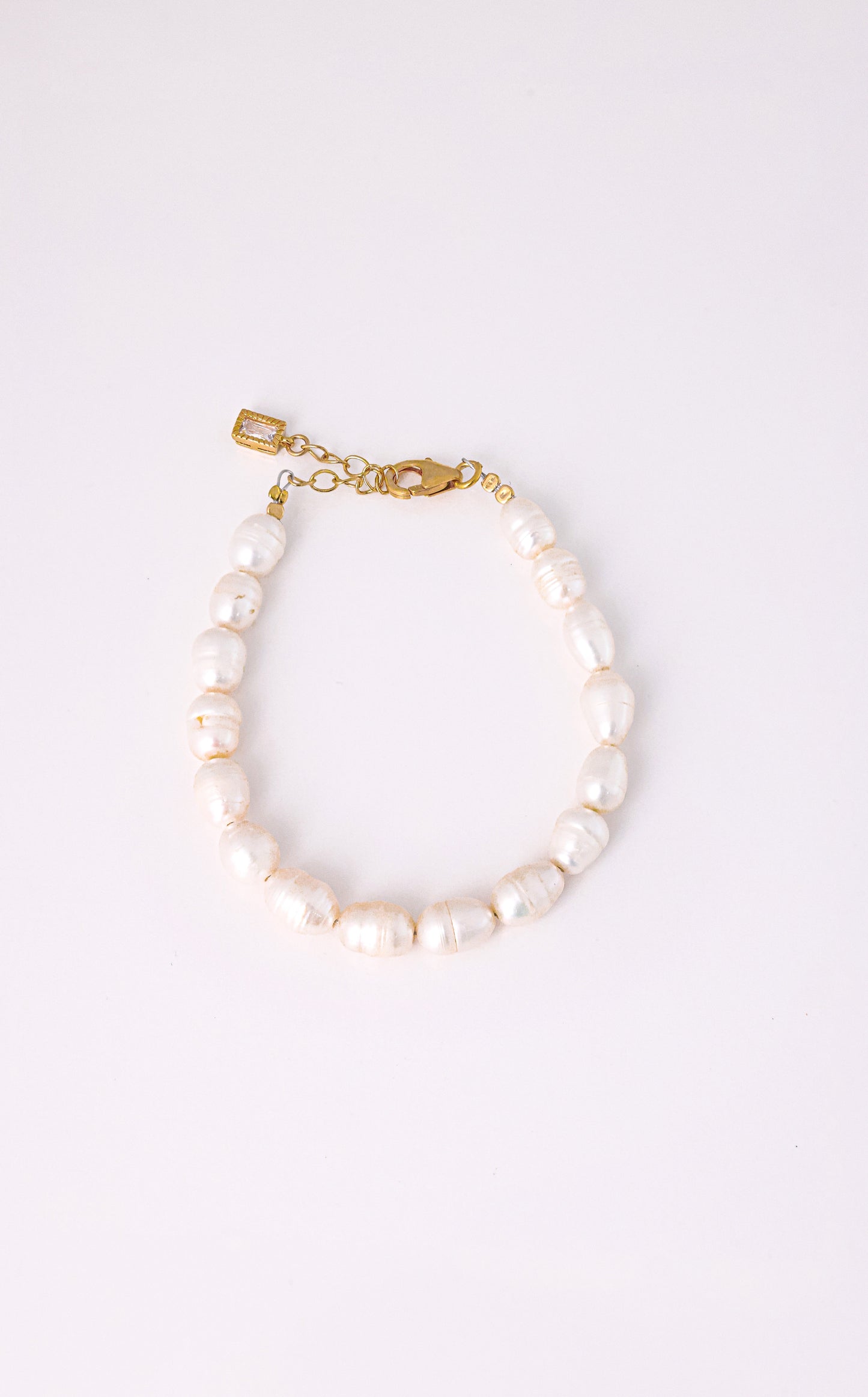 צמיד AMELIA BRACELET פניני בארוק לבנות, סוגר ושרשרת הארכה מזהב עם תליון מלבני, על רקע לבן.