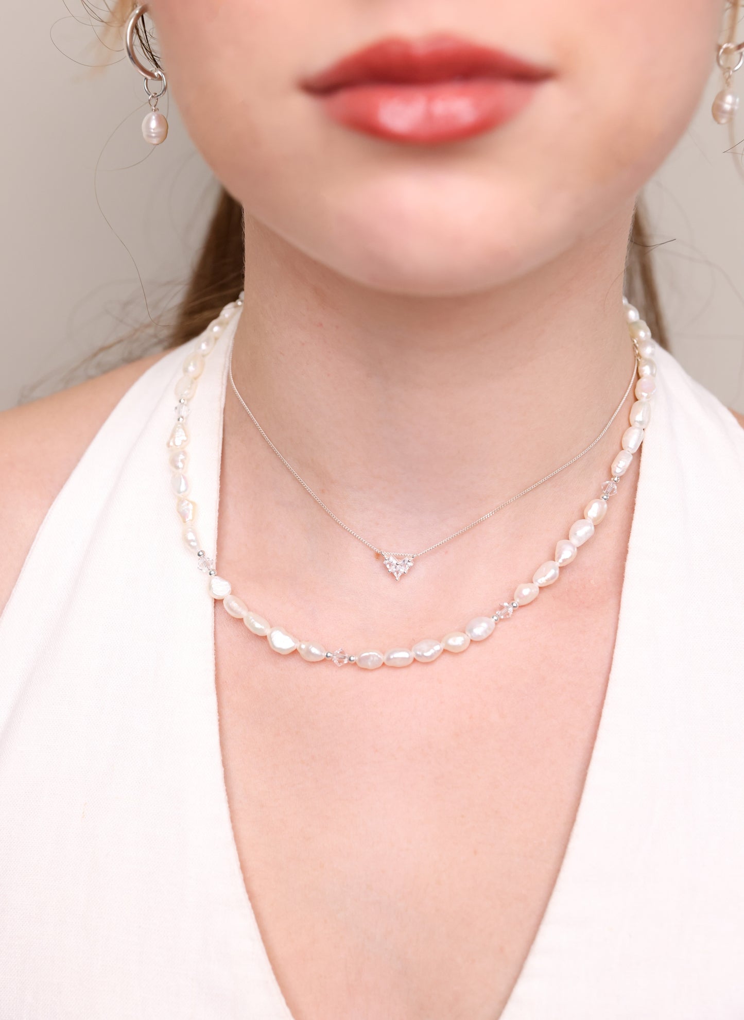 שרשרת ALAMOR QUARTZ SILVER עם תליון לב, בשילוב שרשרת פנינים ועגילי פנינה, על צוואר דוגמנית בתקריב.