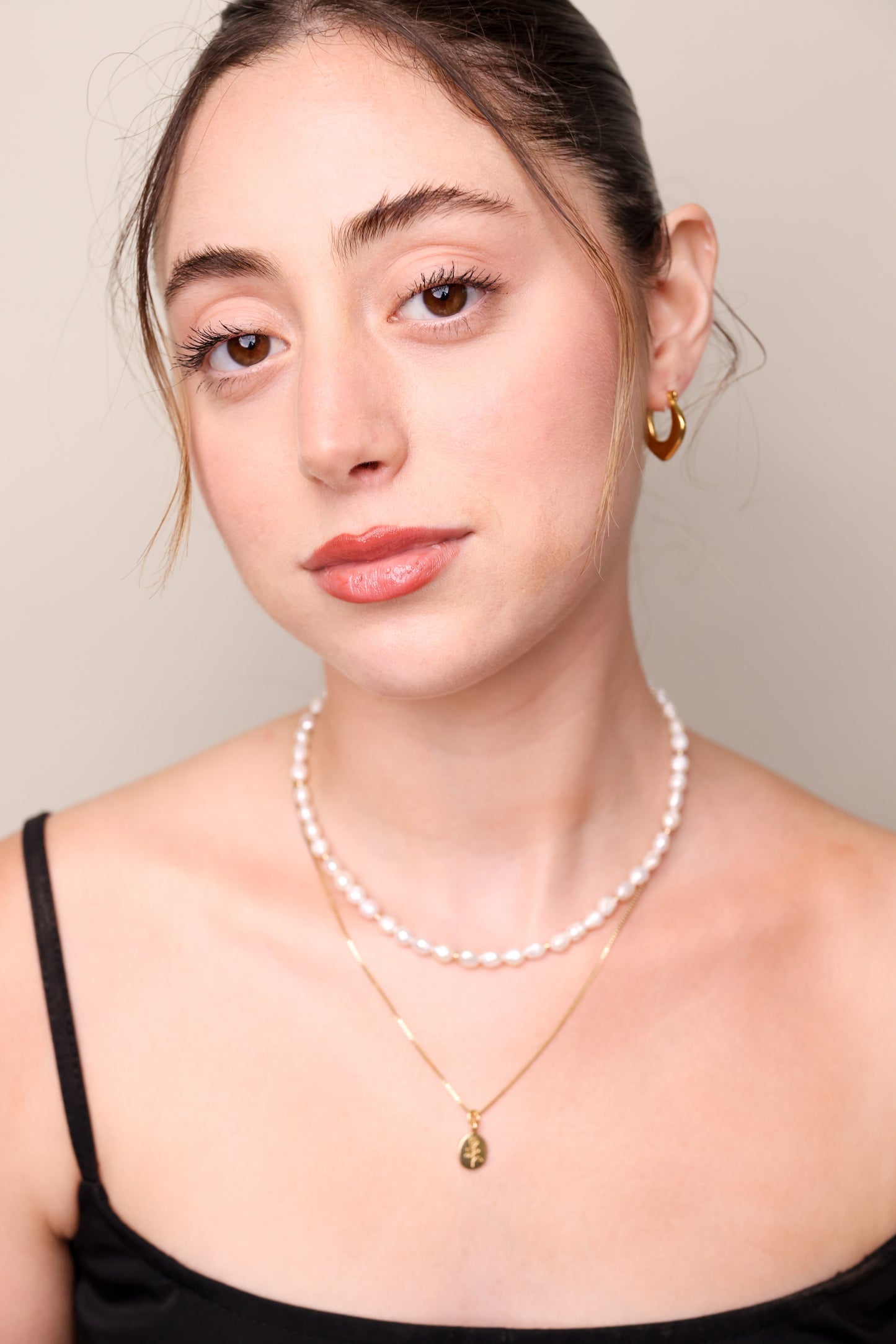 עגילי MICHAL חישוק זהב עבים, בצורת סהר, על אוזן דוגמנית. תקריב בו העגיל מציץ מבעד לשיער אסוף.