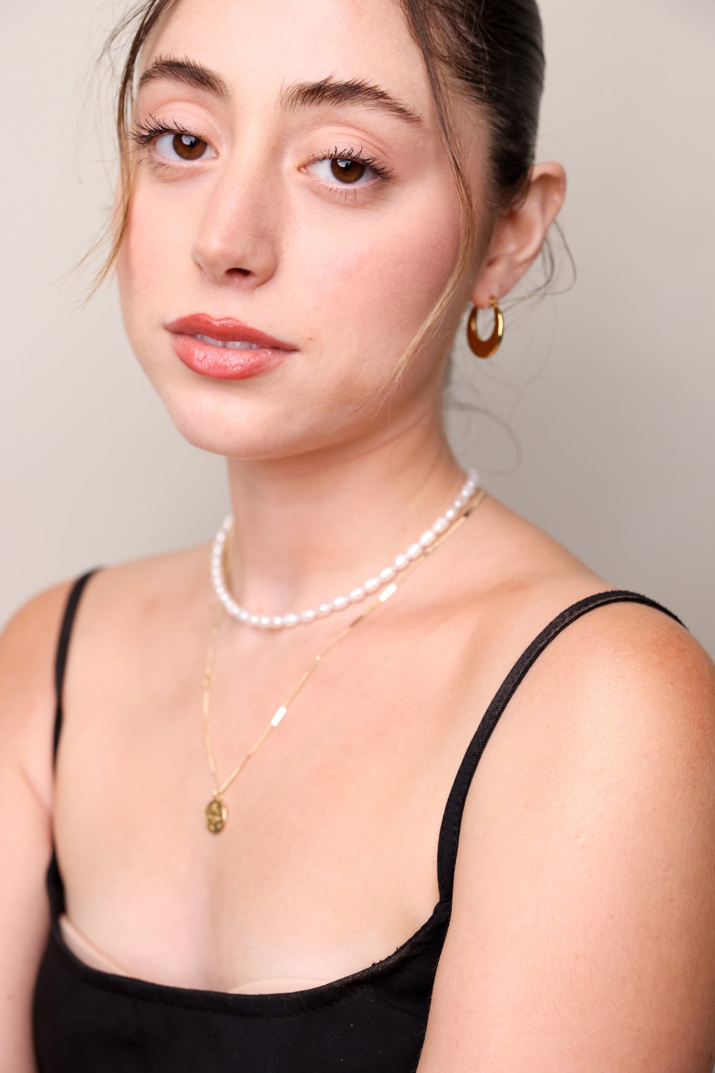 עגילי ÉLENA חישוקי זהב עבים על אוזן דוגמנית, מבט חלקי על הפנים.