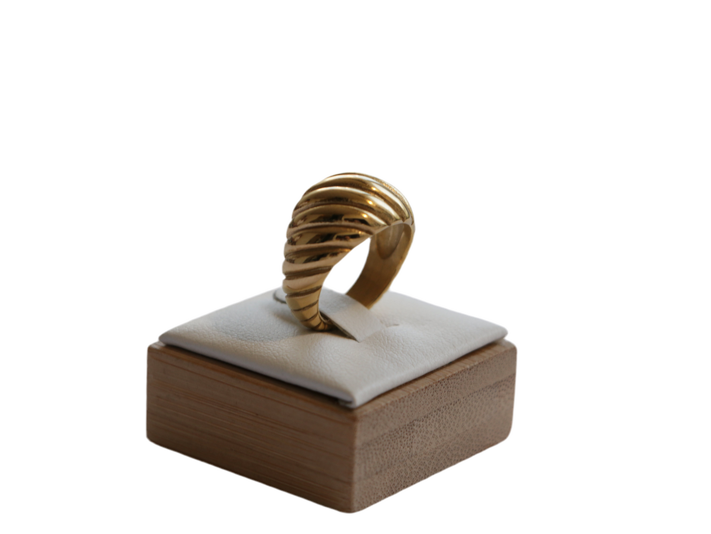 טבעת SHTI מזהב בעיצוב גלי בולט, מוצגת על כרית לבנה, מבט תקריב בזווית קדמית.