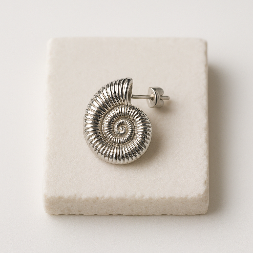 עגיל SHAB SILVER יחיד, כסף מבריק מעוצב כקונכייה ספירלית מצולעת, מונח על אבן בהירה. תקריב על פין העגיל.