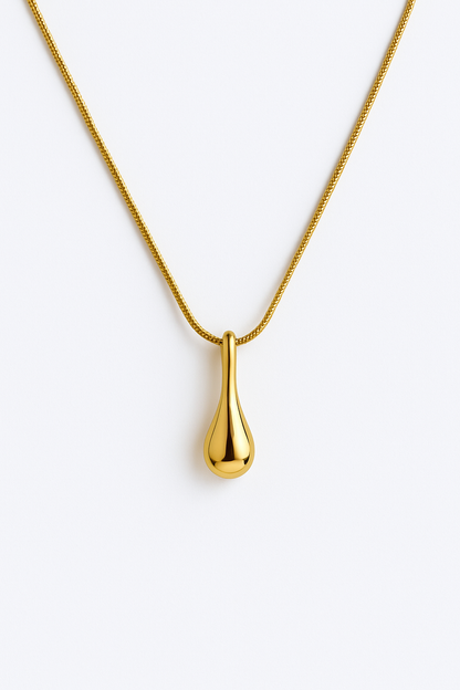 שרשרת OLA זהב מלוטשת, תליון טיפה מבריק צולם מלמעלה על רקע לבן. שרשרת נחש עדינה.