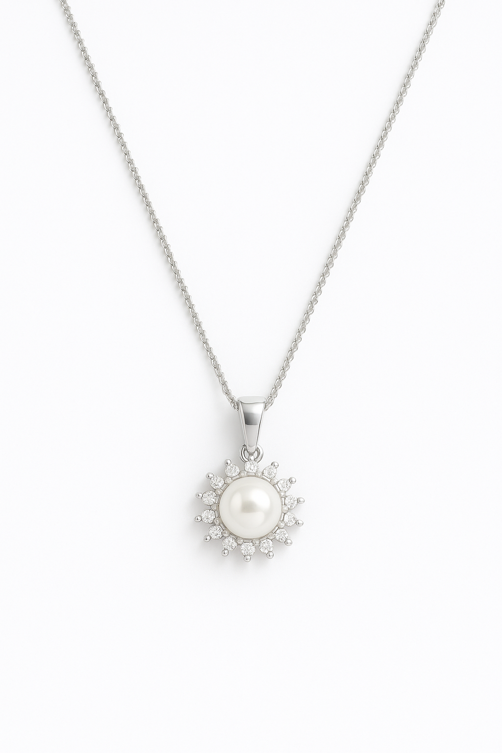 שרשרת ELLA כסופה, תליון עם פנינה לבנה המוקפת אבני זרקון נוצצות בעיצוב דמוי שמש, מבט מלמעלה.