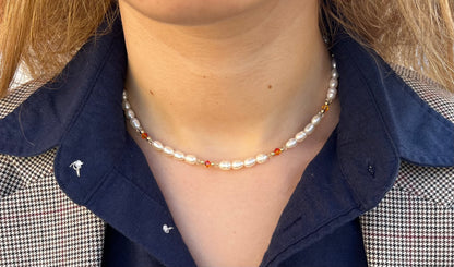 שרשרת ALAMOR APROL GOLD פנינים, חרוזי זהב וחרוזי קריסטל כתומים על דוגמנית, מבט תקריב.