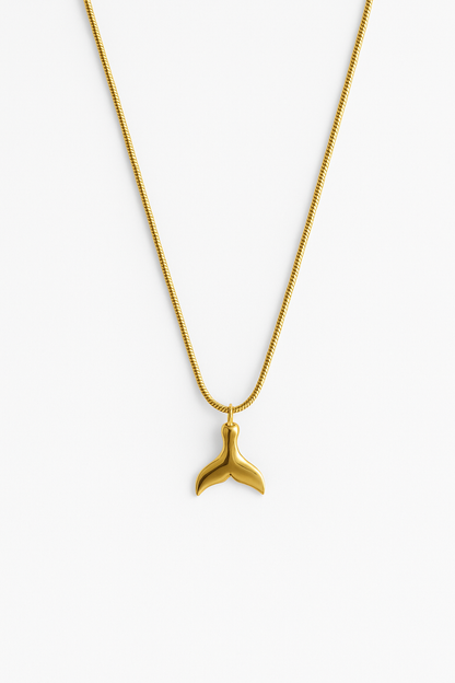 שרשרת SNAP GOLD NECKLACE זהב, תליון זנב לוויתן מבריק ושרשרת נחשית, מצולם מלמעלה על רקע לבן.