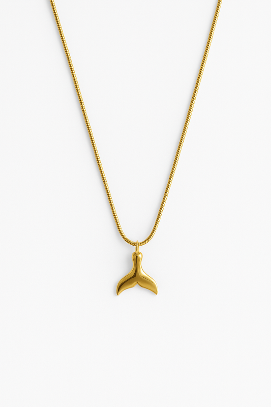 שרשרת SNAP GOLD NECKLACE זהב, תליון זנב לוויתן מבריק ושרשרת נחשית, מצולם מלמעלה על רקע לבן.