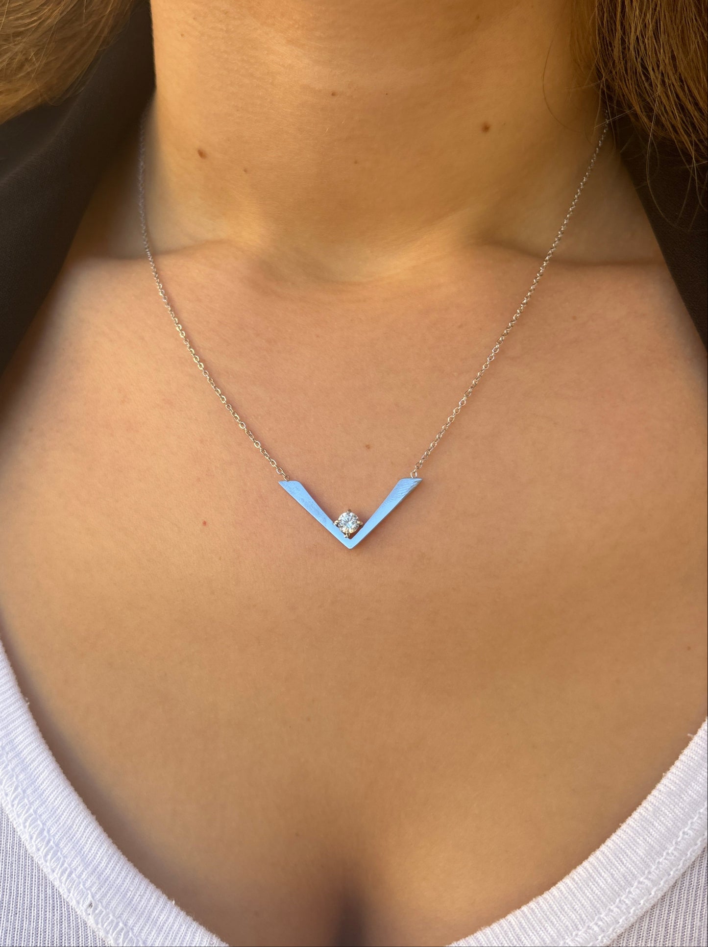 שרשרת GAYA NECKLACE כסף על צוואר דוגמנית, תקריב של תליון V יוקרתי המשובץ יהלום בזהב.