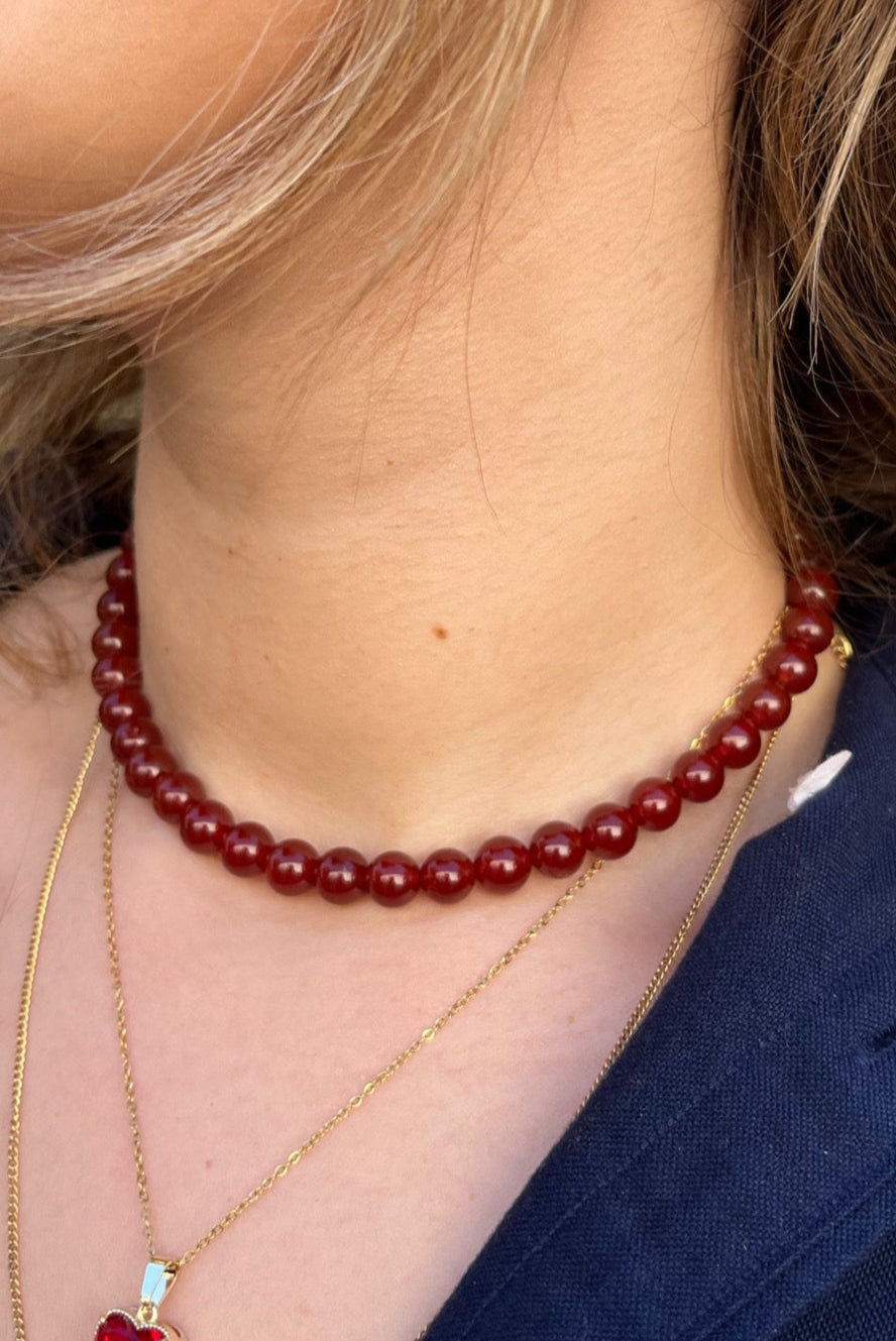 שרשרת ALEN SILVER NECKLACE עם חרוזים אדומים מבריקים, צמודה לצוואר הדוגמנית, משולבת עם שרשרת זהב עדינה.