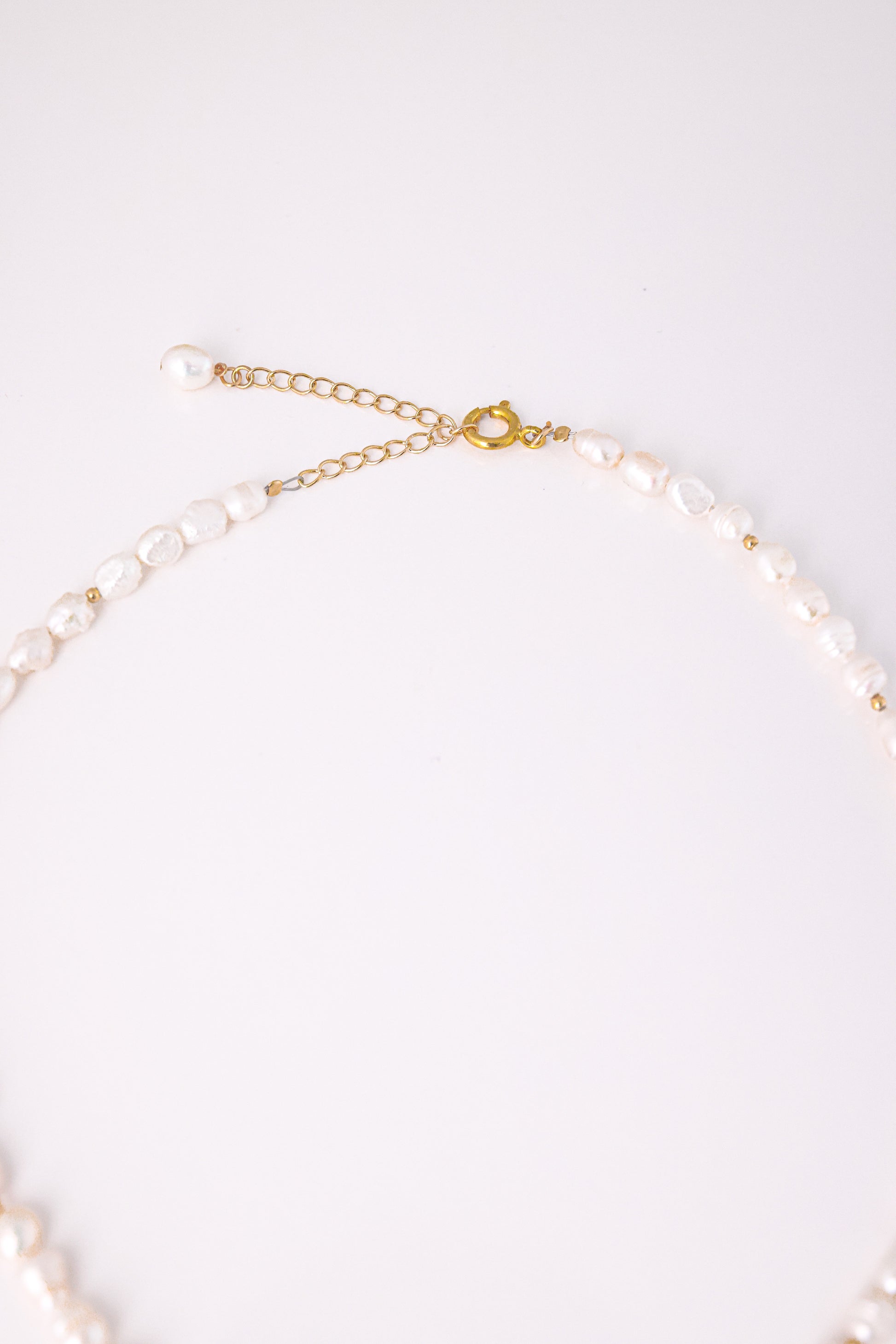 שרשרת BELA NECKLACE GOLD, תקריב על סוגר ושרשרת הארכה מזהב עם פנינה. פנינים לא סדירות משולבות בחרוזי זהב.