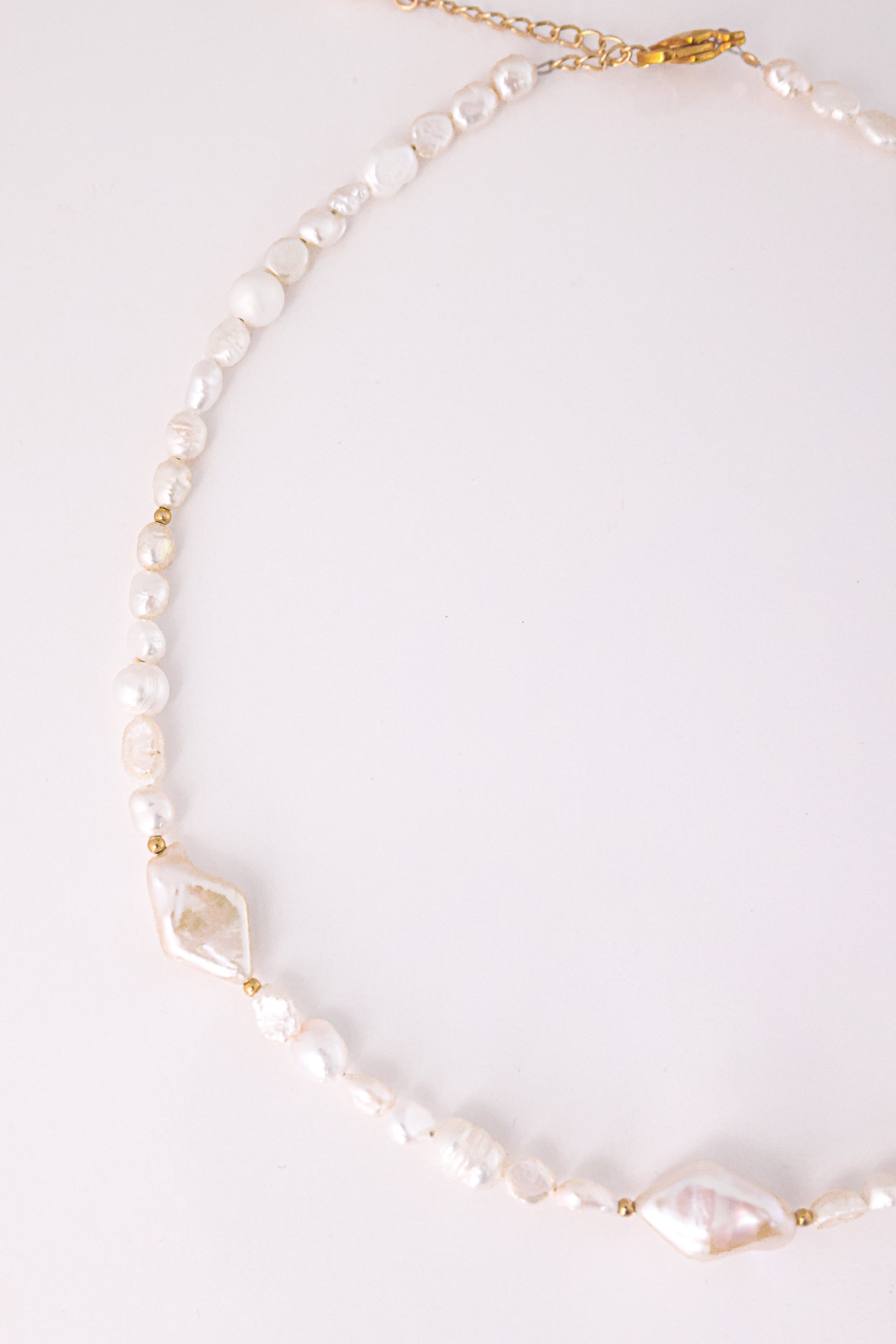 שרשרת SHAI מפניני בארוק בצורות לא סדירות, כולל פניני מעוין שטוחות, עם ללי זהב. צילום מלמעלה על רקע בהיר.