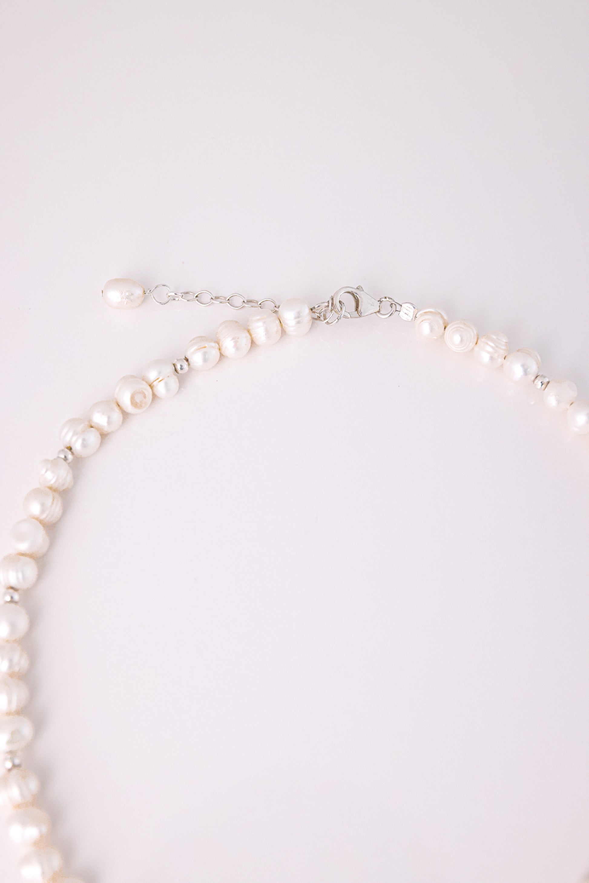 תקריב של סוגר הכסף ושרשרת הארכה של שרשרת GEFEN NECKLACE עם פנינת מים מתוקים בסוף.