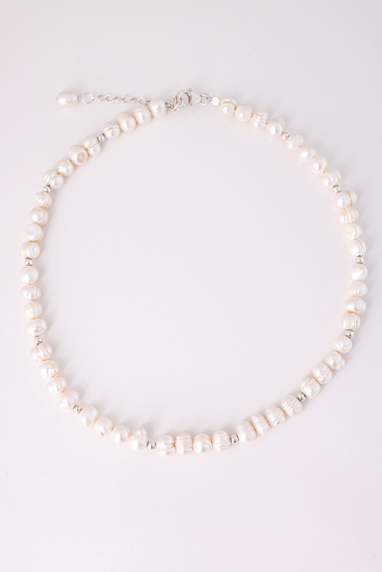 שרשרת GEFEN מפניני מים מתוקים לא סימטריות וחרוזי כסף קטנים. צילום מלמעלה על רקע בהיר, מציג את סוגר הלובסטר ושרשרת ההארכה.