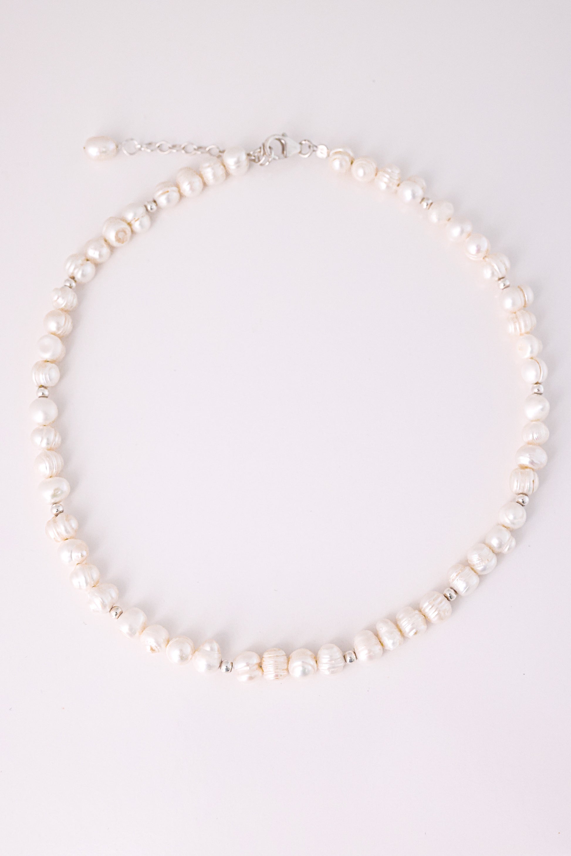 שרשרת GEFEN מפניני מים מתוקים לא סימטריות וחרוזי כסף קטנים. צילום מלמעלה על רקע בהיר, מציג את סוגר הלובסטר ושרשרת ההארכה.