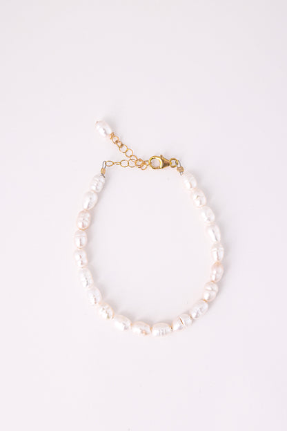 צמיד ANNA BRACELET GOLD, פנינים לבנות לא סדורות, סוגר ושרשרת הארכה מזהב, מצולם מלמעלה על רקע לבן.