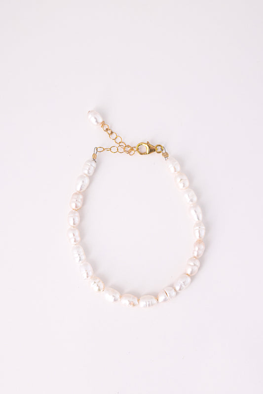 צמיד ANNA BRACELET GOLD, פנינים לבנות לא סדורות, סוגר ושרשרת הארכה מזהב, מצולם מלמעלה על רקע לבן.