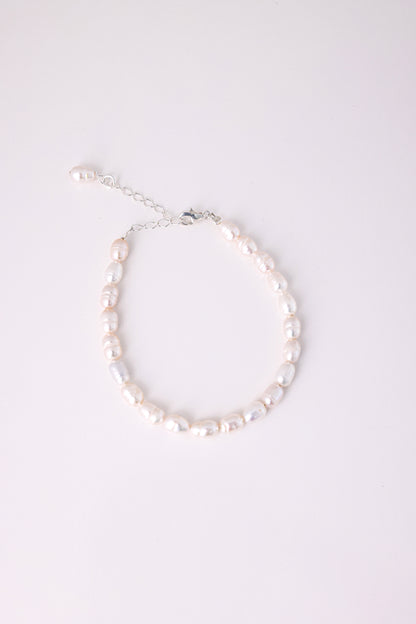 צמיד ANNA BRACELET SILVER פנינים מתורבתות לא סדירות בגוון ורדרד, מצולם מלמעלה עם סוגר ושרשרת הארכה כסופים על רקע לבן.