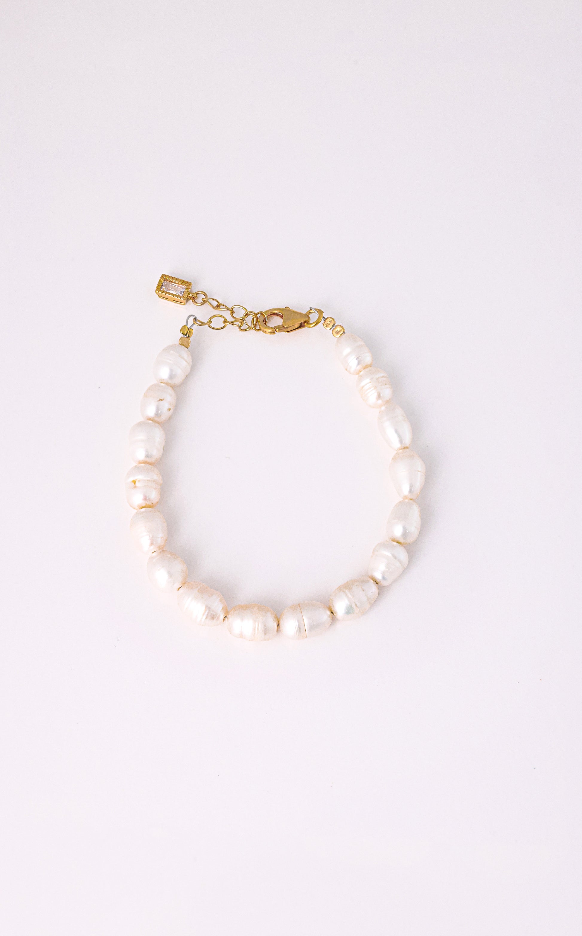 צמיד AMELIA BRACELET פניני בארוק לבנות, סוגר ושרשרת הארכה מזהב עם תליון מלבני, על רקע לבן.