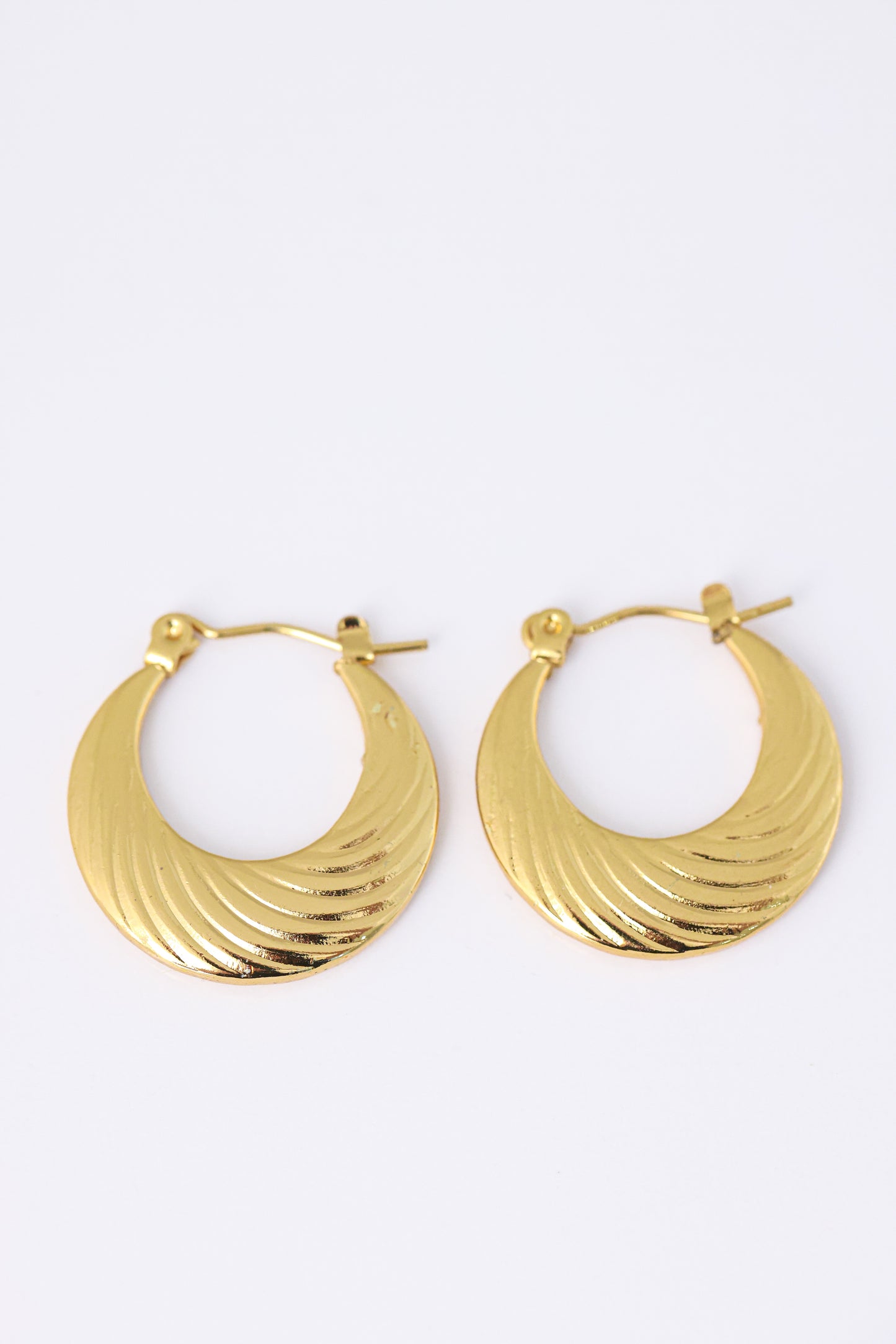 עגילי MIKA EARRINGS מזהב, בצורת סהר עם טקסטורת פסים מעוגלים, צולמו בתקריב על רקע לבן.