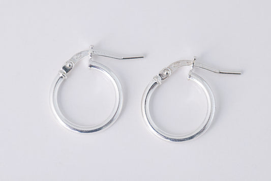 עגילי חישוק AMIT EARRINGS XS כסף מבריקים, מונחים בזווית קלה על רקע לבן, הסוגרים פתוחים וסימון 925 נראה בבירור.