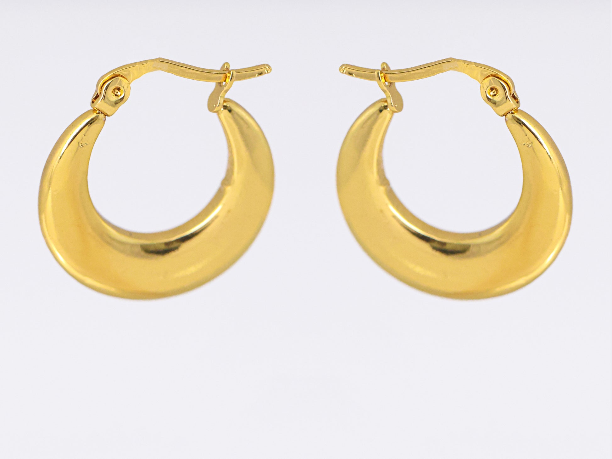 עגילי ÉLENA זהב של Lidi, חישוקים עבים מבריקים בצורת סהר, מבט חזיתי על מנגנון סגירה מפרקי.