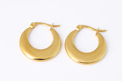 עגילי ÉLENA EARRINGS זהב מבריקים, חישוקים עבים מונחים על רקע לבן, מבט תקריב עליון.