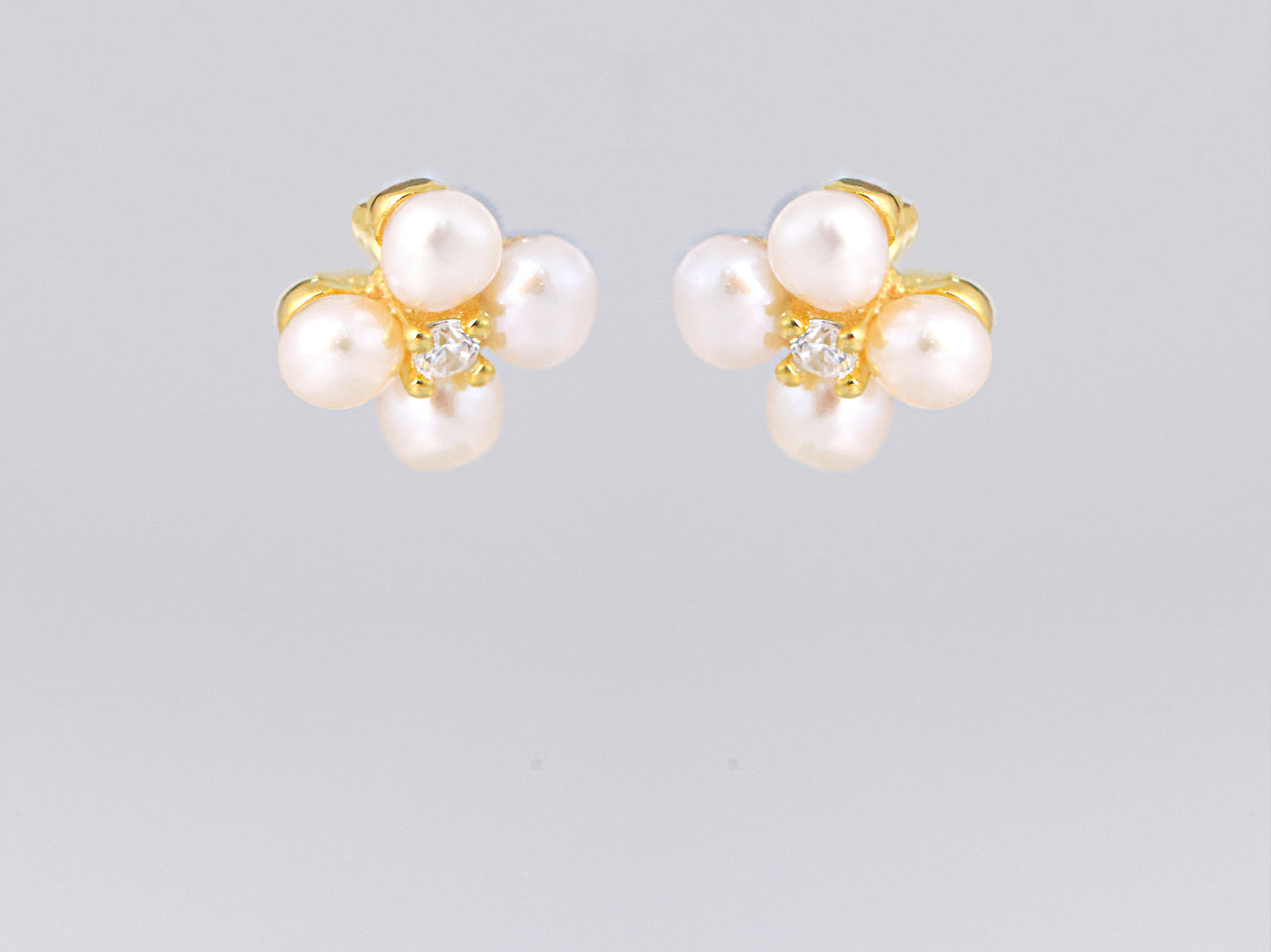 עגילי NOA EARRINGS GOLD מזהב, מבט מלפנים על תלתן פנינים לבנות ואבן נוצצת במרכז.