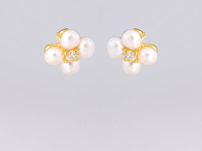 עגילי NOA EARRINGS GOLD מזהב, מבט מלפנים על תלתן פנינים לבנות ואבן נוצצת במרכז.