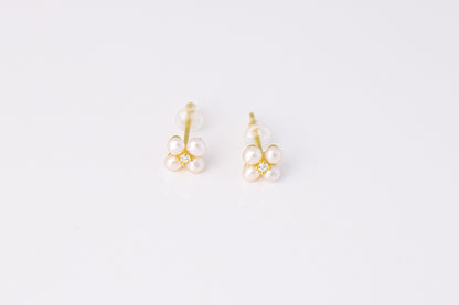 עגילי NOA EARRINGS GOLD, תקריב של זוג עגילים מזהב, כל אחד פרח מ-4 פנינים ויהלום במרכז, על רקע לבן.