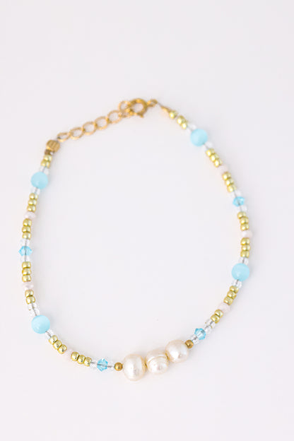 צמיד KARIN BRACLET: חרוזי זהב, תכלת וקריסטל שקופים, עם שלוש פנינים טבעיות במרכז ואבזם זהב.