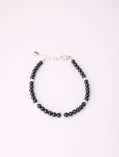 צמיד RONA BRACELET חרוזים שחורים מבריקים וכדורי כסף מפרידים, מבט מלמעלה על רקע לבן. כולל סוגר אבזם ושרשרת הארכה.