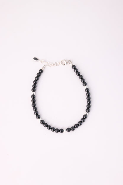 צמיד RONA מעוצב מחרוזים שחורים מבריקים עם חרוז כסף בודד, סוגר ושרשרת הארכה כסופים, מצולם מלמעלה על רקע לבן.