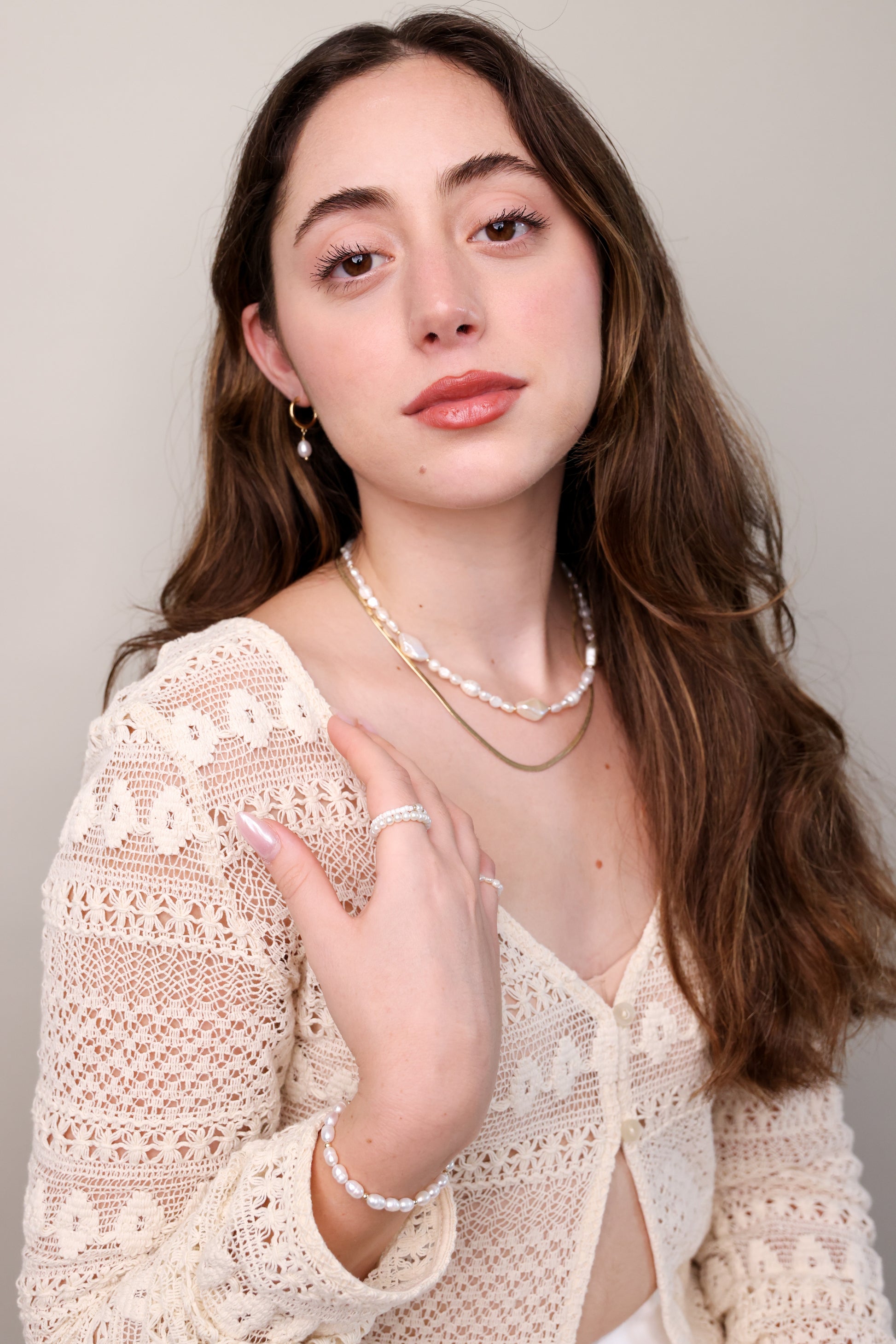 דוגמנית עונדת שרשרת SHAI NECKLACE פנינים טבעיות ושרשרת זהב שטוחה, יד על הכתף.