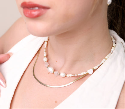 שרשרת LIHI NECKLACE כפולה על צוואר דוגמנית: שרשרת נחש זהובה ושרשרת פנינים, אבני רוז קוורץ וחרוזים. מבט תקריב.