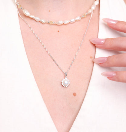 שרשרת ELLA NECKLACE כסף עם תליון פנינה עגולה ואבנים זוהרות על דוגמנית. בשילוב שכבת שרשרת פנינים ואבנים צהובות.