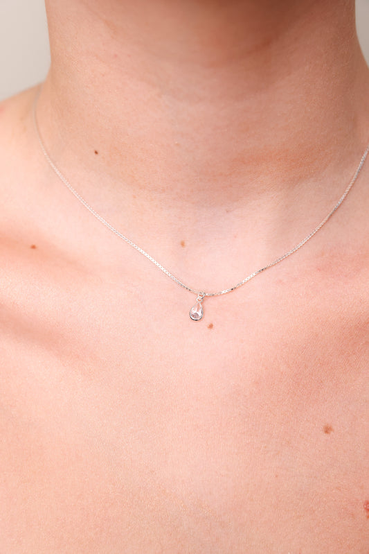 מבט תקריב על צוואר דוגמנית עונדת שרשרת DARIA NECKLACE כסף עם תליון טיפה שקוף.