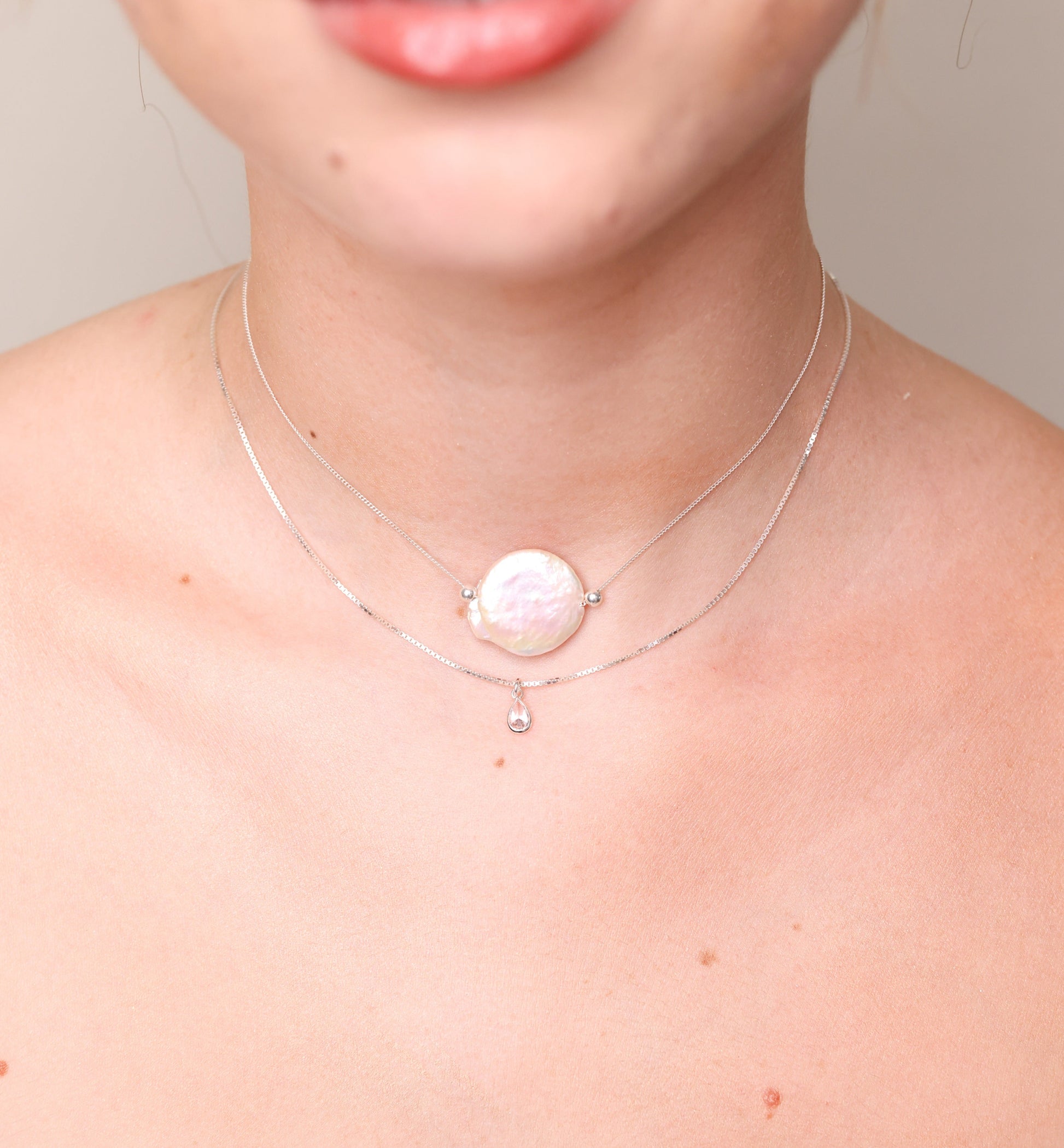 שרשרת DANI כסף שכבות על צוואר דוגמנית, פנינה בארוק שטוחה עם טיפת קריסטל עדינה.