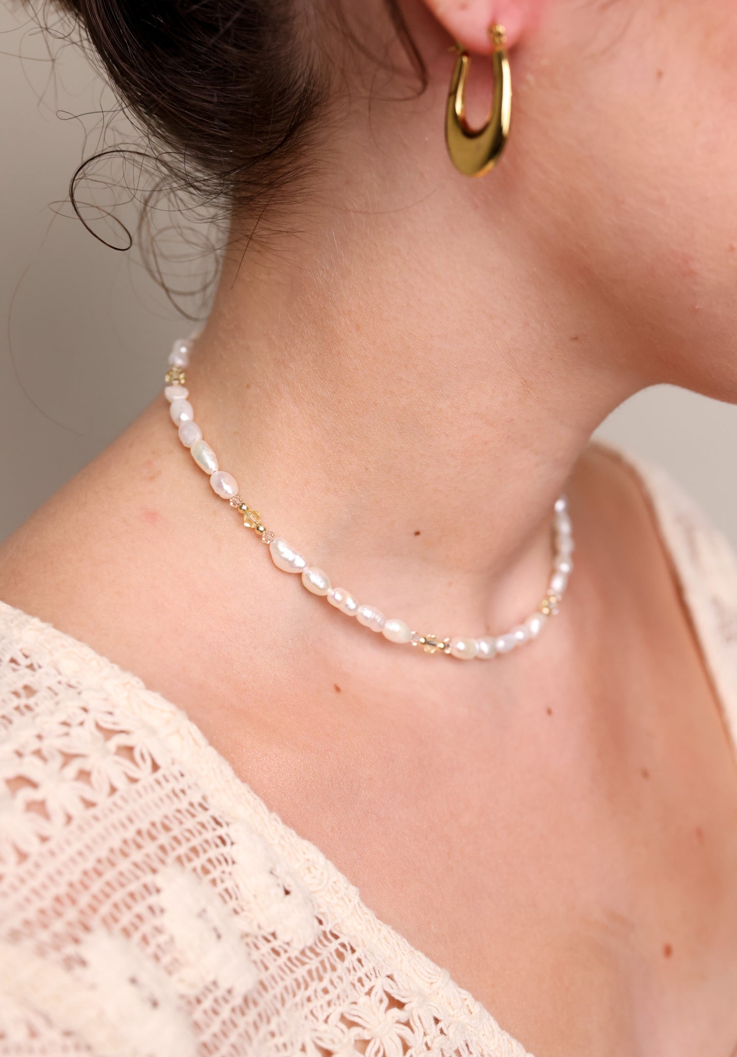 שרשרת ALAMOR YELLOW GOLD פניני מים מתוקים ופרטי זהב, בתקריב על צוואר דוגמנית בזווית צדדית, עם עגיל חישוק.