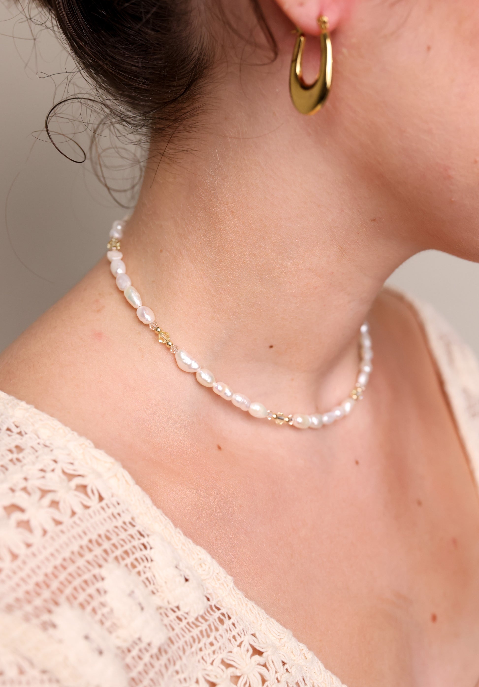 שרשרת ALAMOR YELLOW GOLD פניני מים מתוקים ופרטי זהב, בתקריב על צוואר דוגמנית בזווית צדדית, עם עגיל חישוק.