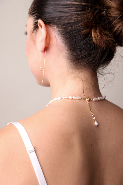 דוגמנית מציגה מאחור: עגיל ALAMOR QUARTZ GOLD מושחל ושרשרת פנינים טבעיות עם סוגר זהב ופנינה תלויה.