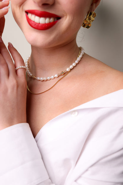 שרשרת ADIA שכבות (פנינים וזהב) על צוואר דוגמנית חייכנית, חולצה לבנה, עגיל זהב מפורט ויד עם טבעת פנינים.
