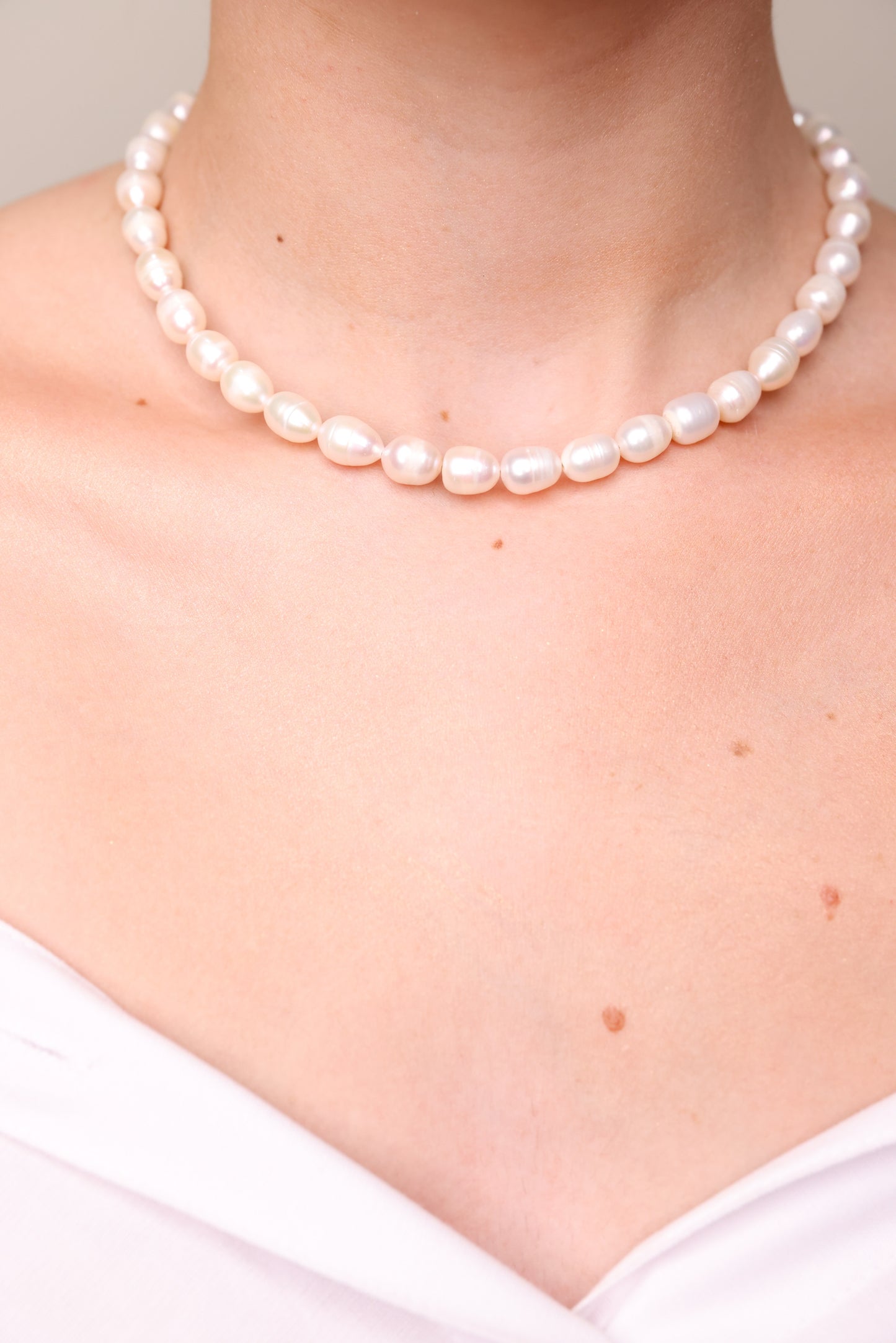 שרשרת AMELIA צ'וקר של Lidi, פניני ברוק לבנות עוטפות צוואר דוגמנית בחולצה לבנה, תקריב.