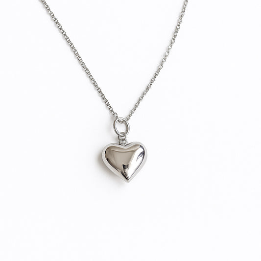 שרשרת FAT LOVE SILVER NECKALCE כסף, תליון לב מבריק ונפוח, מצולם מלמעלה על רקע לבן, פרטי השרשרת העדינה.