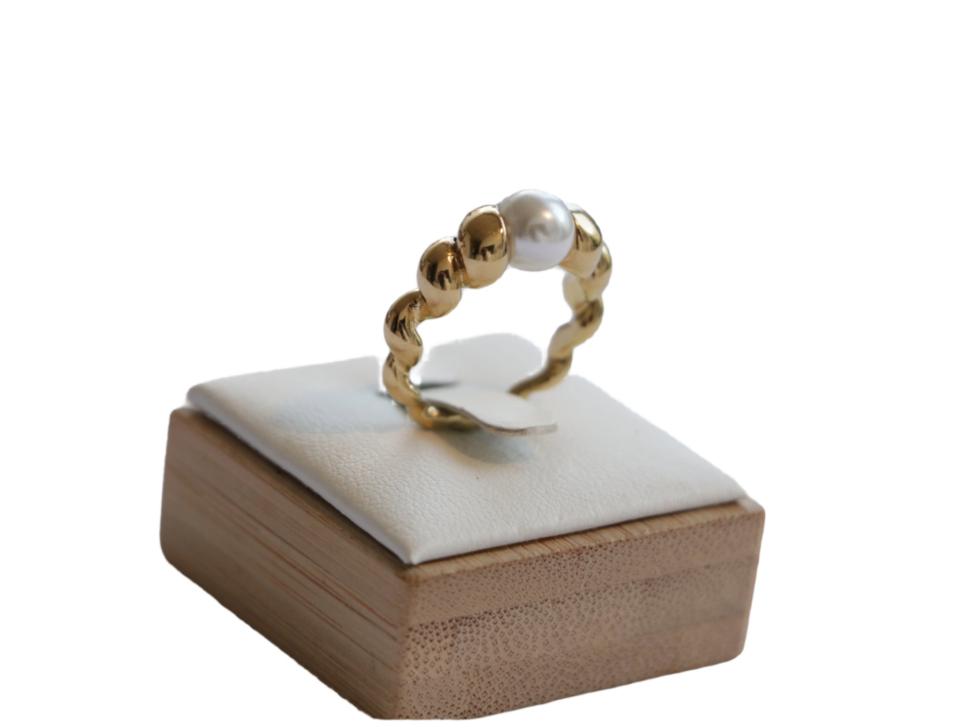 טבעת LOPE RING מזהב, בעיצוב פיתולים עם פנינה לבנה, מוצגת בתקריב על סטנד עץ.