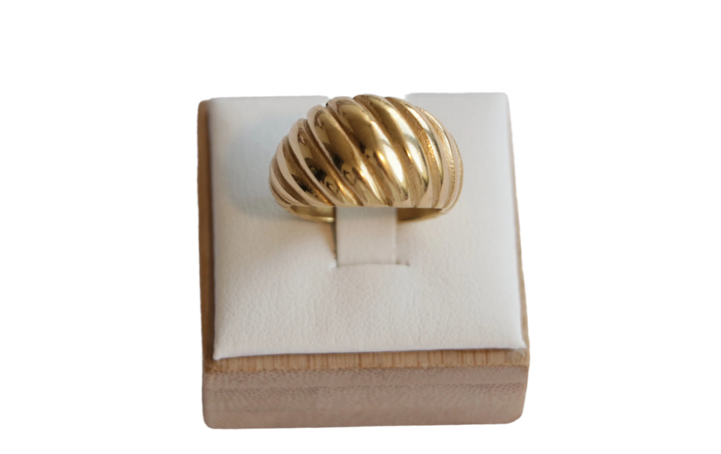 טבעת SHTI זהב עבה ומבריקה, בעלת טקסטורת פסים גליים, על מעמד עץ-לבן, מבט קדמי.