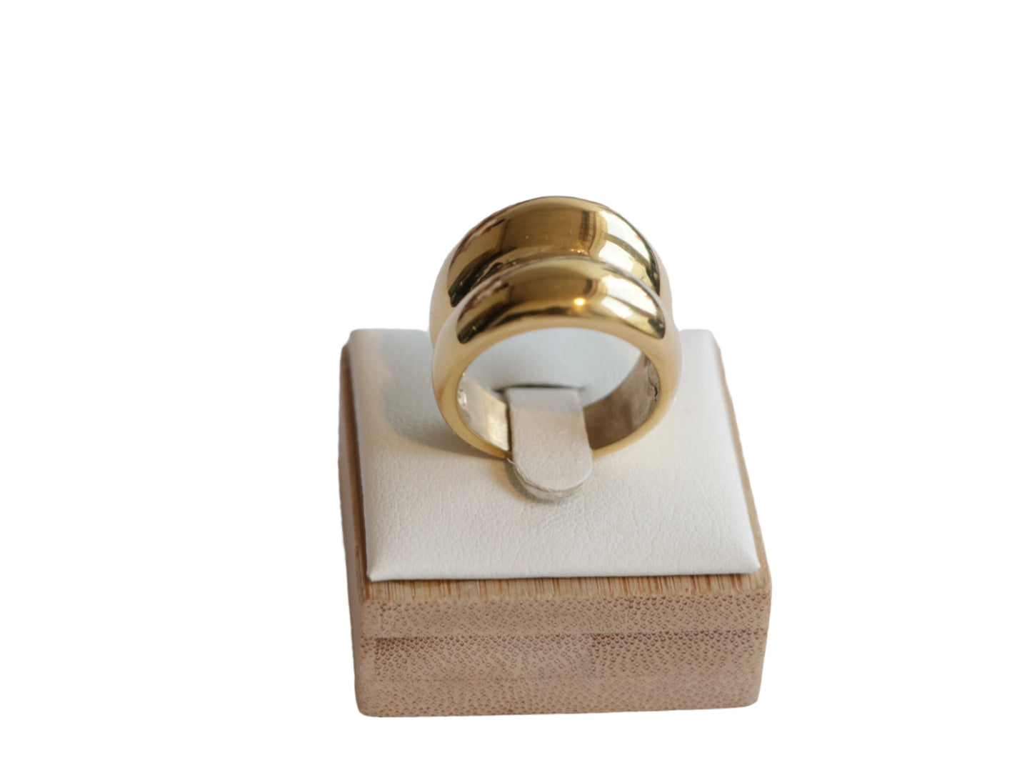 טבעת RAND זהב רחבה ומבריקה, מוצגת על סטנד תצוגה מעץ בהיר, זווית קדמית מוגבהת.