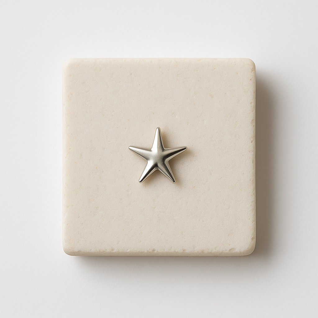 עגיל STAR EARRINGS בודד מכסף מבריק בצורת כוכב נפוח, מונח על משטח אבן בהיר מרובע, מבט תקריב.