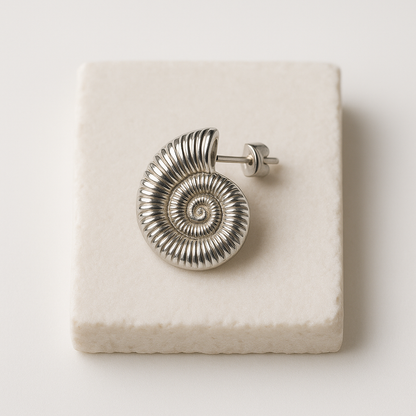עגיל SHAB SILVER יחיד, כסף מבריק מעוצב כקונכייה ספירלית מצולעת, מונח על אבן בהירה. תקריב על פין העגיל.